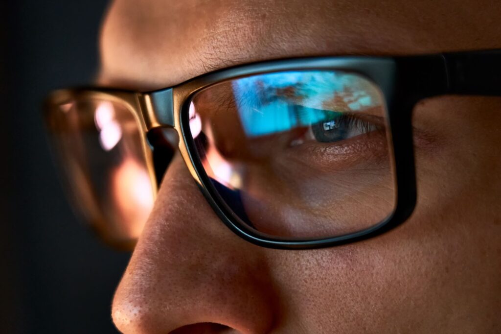 A man is wearing reading glasses to help with reading his computer screen.