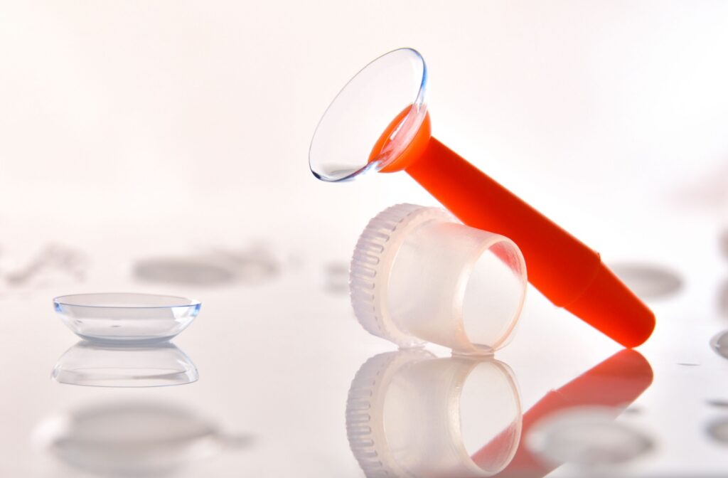 Scleral contact lens with insertion tool and lens case on a clean reflective surface.