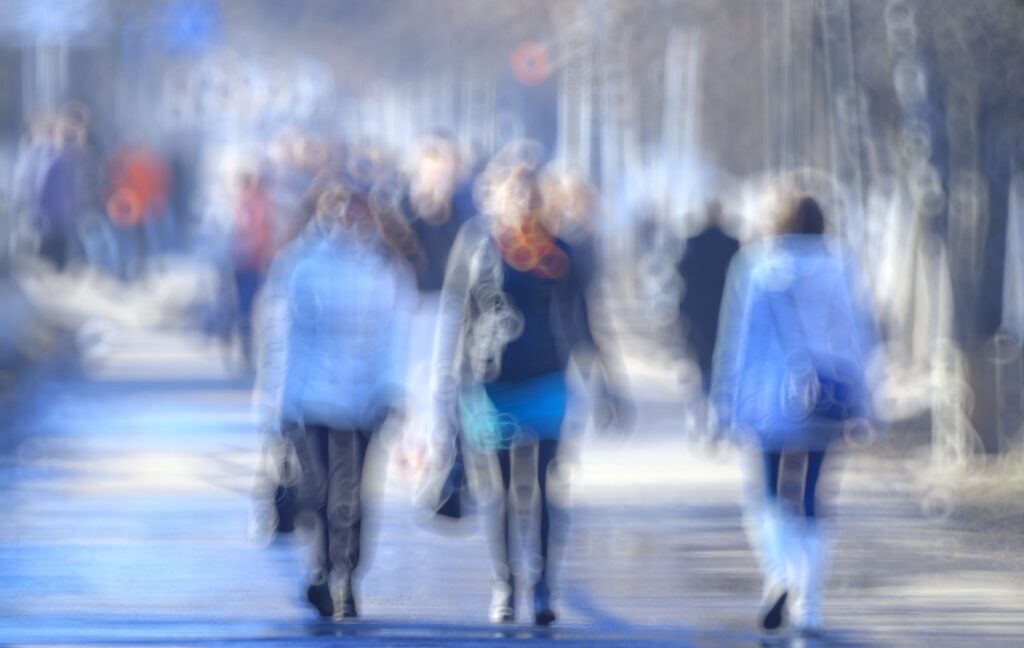 Three people walk down the street. They appear to be blurry from vision affected by diabetic retinopathy.