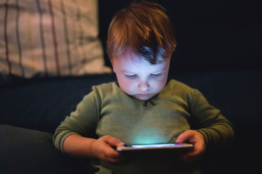 Toddler boy playing a game on a bright smartphone